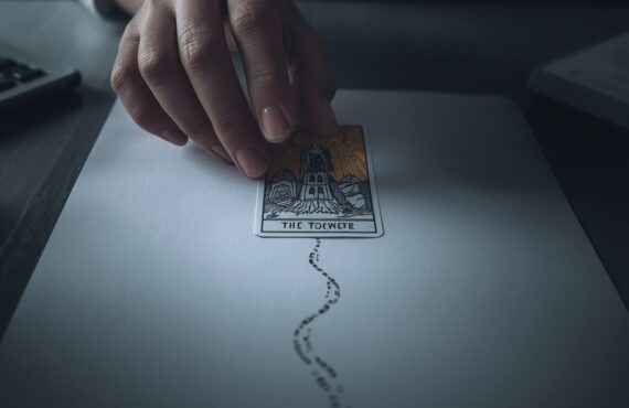 La Main D’une Personne Est Montrée Planant Au Dessus D’une Seule Carte De Tarot Cruciale
