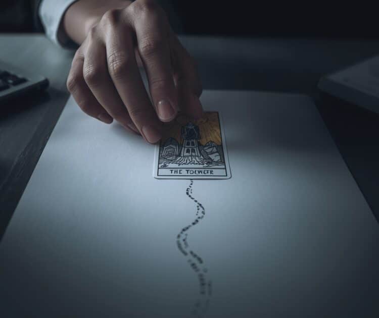 La Main D’une Personne Est Montrée Planant Au Dessus D’une Seule Carte De Tarot Cruciale